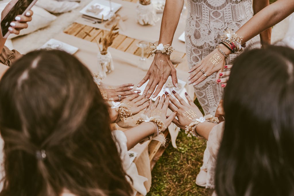 A group of bridesmaids at a bachelorette party showing hands with decorative henna and accessories, creating a joyful moment.