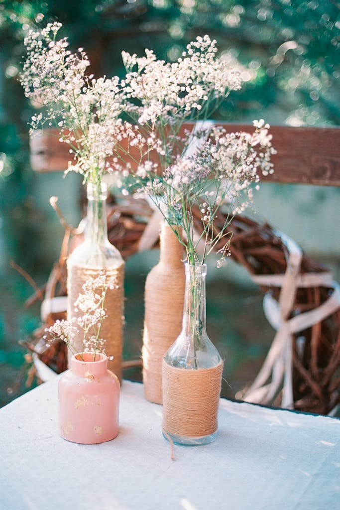 Charming rustic decor with flowers in bottles on a table outdoors.